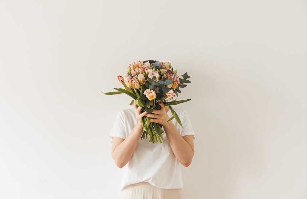 Woman holding flowers in front of her face